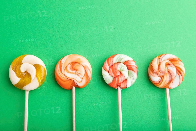 Four lollipop candies on green pastel background. copy space, top view, flat lay