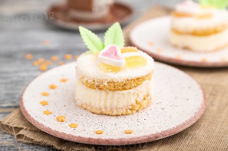 Decorated cake with milk and coconut cream with cup of coffee on a gray wooden background and linen textile. Side view, close up, selective focus