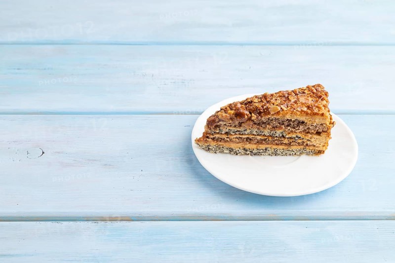 Walnut and hazelnut cake with caramel cream on blue wooden background. side view, copy space