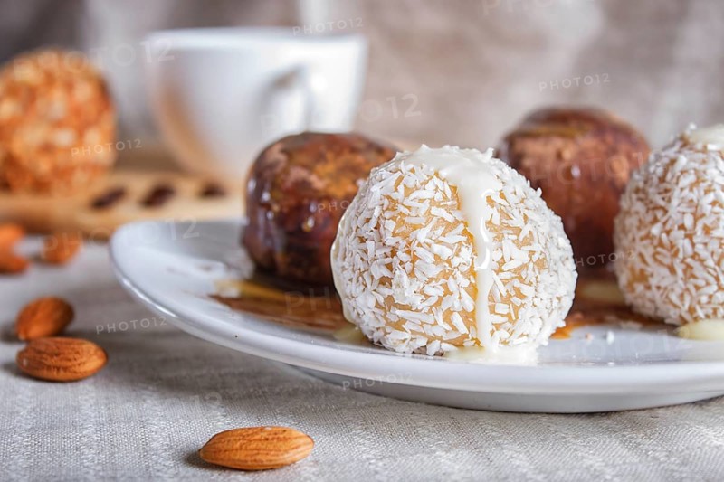 Energy balls cakes with chocolate caramel and coconut on white plate on linen napkin, selective focus, close up