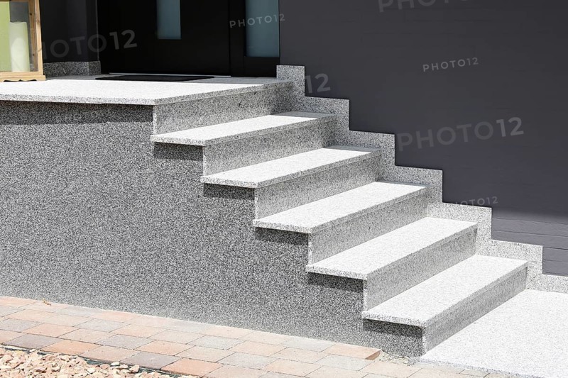 Block stepped staircase with plinth made of coloured stone plaster as an entrance staircase to a residential building