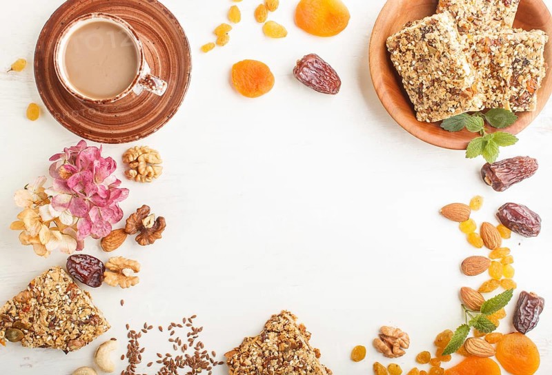 Homemade granola from oat flakes, dates, dried apricots, raisins, nuts with a cup of coffee on a white wooden background. Top view, flat lay, copy space, frame form