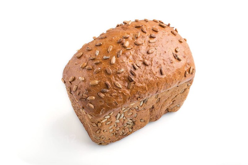 Fresh yeast free homemade bread with sunflower seeds isolated on white background. side view, close up