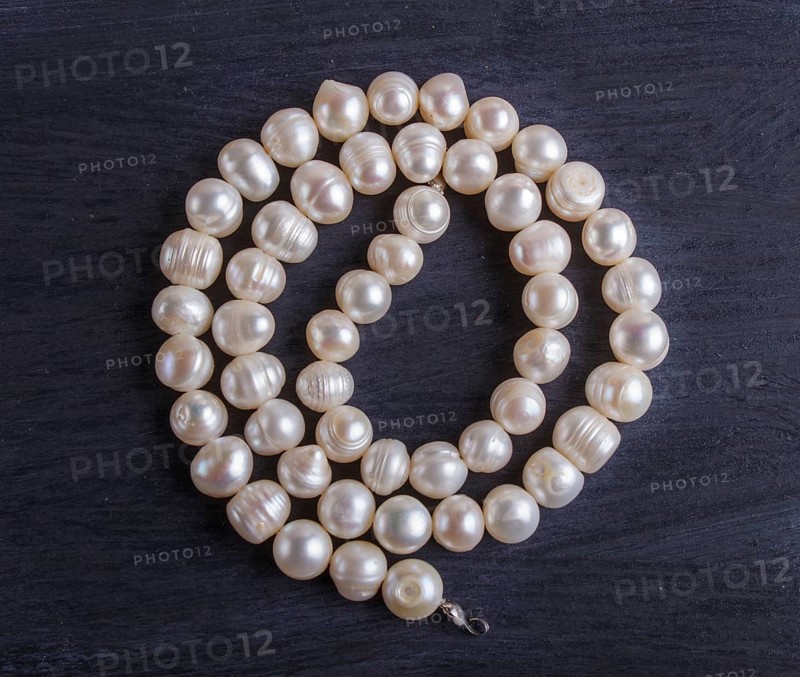White pearl beads on a black background. top view, close up