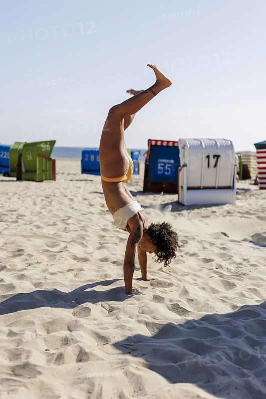 Young woman doing a handstand on the North Sea island of Borkum, 18/05/2024