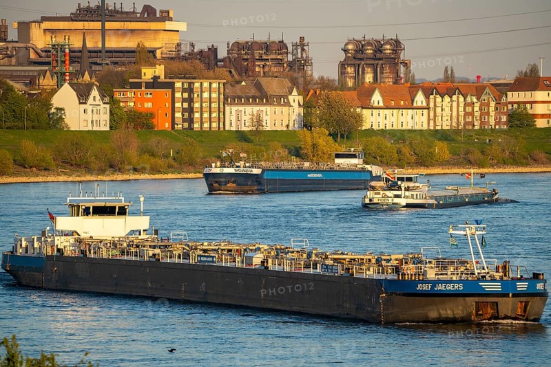 Cargo ships on the Rhine near Duisburg-Laar, houses on Deichstraße, industrial backdrop of the ArcelorMittal Hochfeld GmbH steel wire plant, North Rhine-Westphalia, Germany, Europe