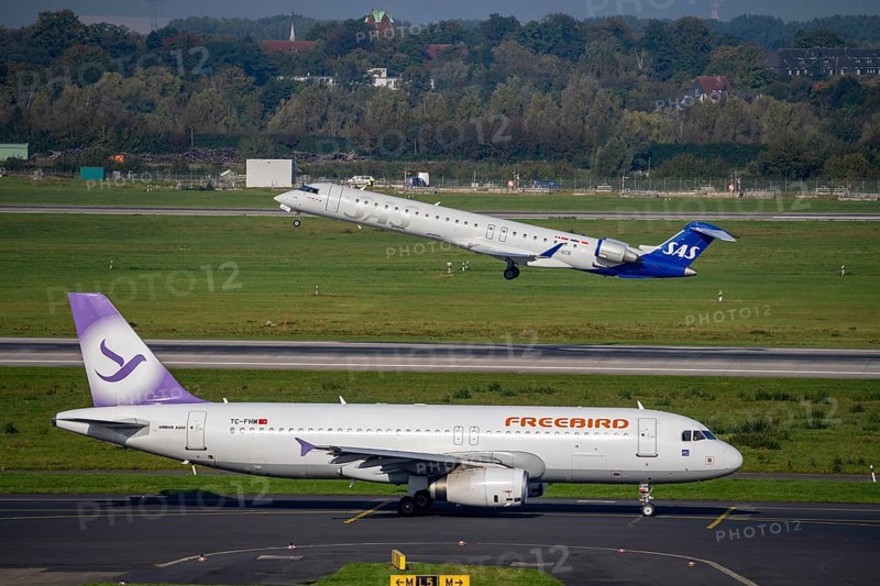 Düsseldorf Airport, SAS Scandinavia Bombardier CRJ-900 on take-off, Freebird Airbus A320 on the taxiway