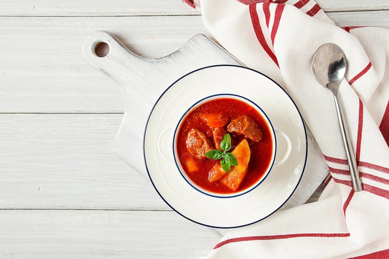 Potatoes stewed with meat, in tomato sauce, with spices and herbs, no people, on a white table
