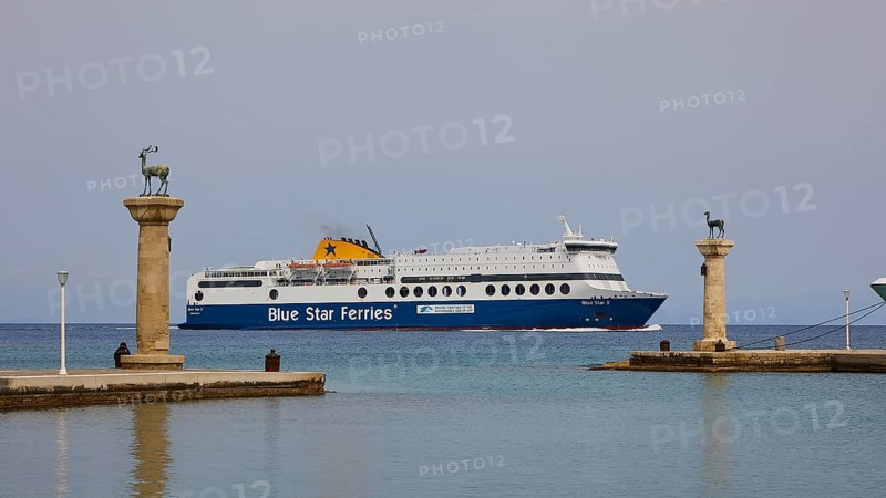 Ferry boat sailing between columns with statues on blue sea, Deer statue, Deer statue, Mandraki harbour, harbour area, European roe deer, Rhodes town, Rhodes, Dodecanese, Greek Islands, Greece, Europe