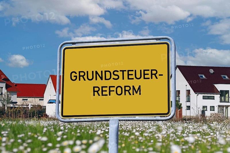 Symbolic image of property tax reform: Town sign with the inscription GRUNDSTEUERREFORM in front of a new development area (Composing)