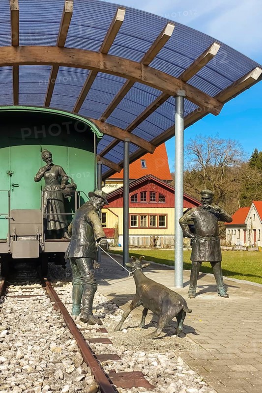 Durlesbach railway station, opened in 1849 and decommissioned in 1984, railway monument, railway memorial, group of figures by the artist René Auer, group of sculptures, scene from the song Auf de schwäbische Eisebahne, billy goat, woman, farmer, conductor, s Bäuerle, Konduktör, s Weible, bronze figures, Königlich Württembergischen Staats-Eisenbahnen, station building at the back right, Durlesbach, Reute, Bad forest lake, Upper Swabia, Baden-Württemberg, Germany, Europe