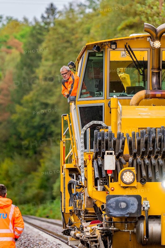 Employees in orange safety clothing next to yellow railway machine, track construction Hermann Hesse Bahn, Calw district, Black Forest, Germany, Europe