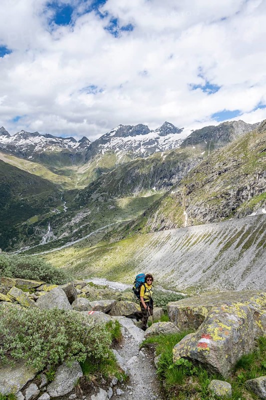 Mountaineer on a hiking trail in front of a picturesque mountain landscape, rocky mountain peaks with snow, valley Zemmgrund with Zemmbach, mountain panorama with summit Großer Mörchner, Berliner Höhenweg, Zillertal Alps, Tyrol, Austria, Europe