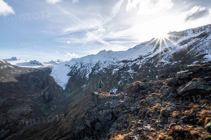 Mountaineer standing on a rock, surrounded by an impressive mountain landscape with snow-covered peaks in autumn View of Gurgler Ferner with summit Hochwilde and Falschungsspitze, Ötztal Alps, Tyrol, Austria, Europe