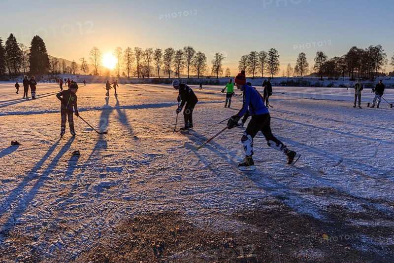 People playing ice hockey on a lake, evening light, sunbeams, Staffelsee, Murnau, foothills of the Alps, Bavaria, Germany, Europe