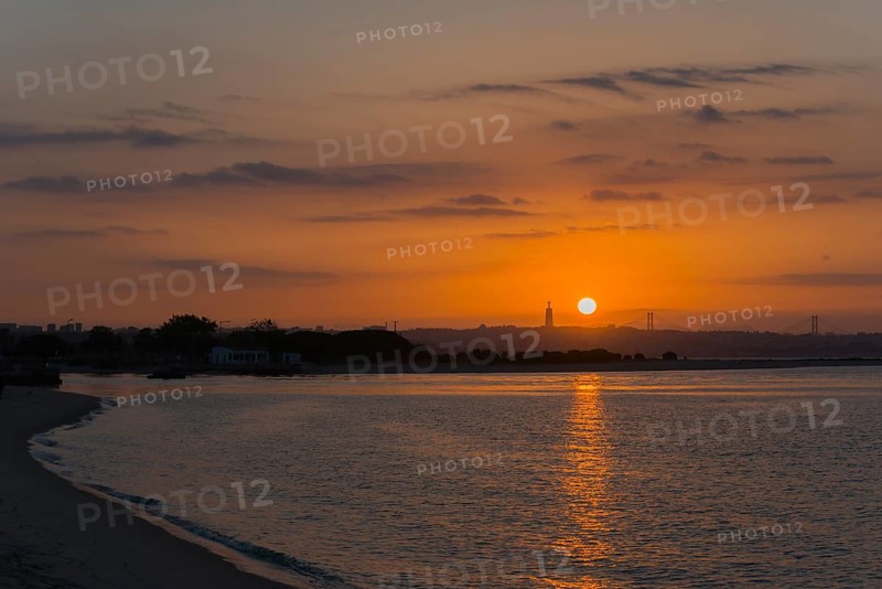 Peaceful coastal scene at sunset, the light reflects in the calm water while the sky glows in warm tones, Cristo Rei statue, Ponte 25 de Abril, 25 April Bridge, Suspension bridge over the Tagus, Lisbon, Lisboa, Portugal, Europe