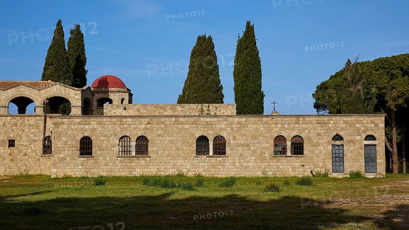 Monastery of Our Lady of Mount Filerimos, Old stone wall of a historic building with tall cypresses in the background under a bright sky, Filerimos, hill not far from Rhodes town, Ancient State of Ialyssos, Rhodes, Dodecanese, Greek Islands, Greece, Europe