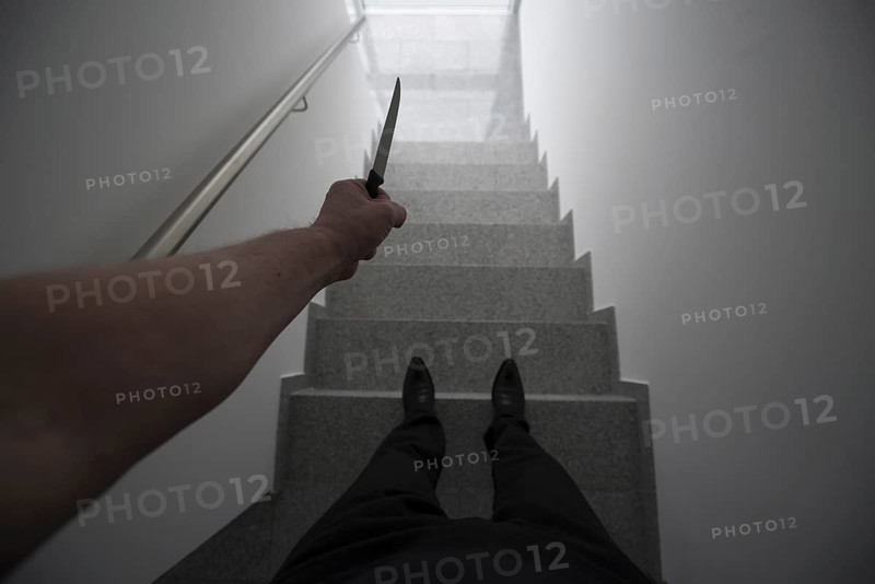 Personal Perspective on a Violent Man Holding a Knife in a Staircase with a Window Light in Switzerland