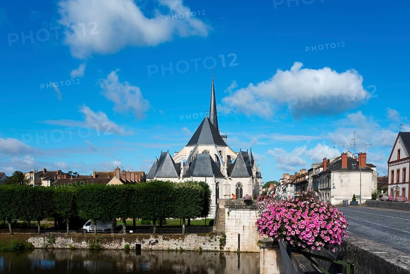 Kirche in einem kleinen Dorf mit klarblauem Himmel und grünen Bäumen, Blumen auf einer Brücke und ruhigem Wasser, Kirche, Église Saint-Jean-Baptiste, Nemours, Fluss Loing, Département Seine-et-Marne, Region Île-de-France, Ile-de-France, Frankreich