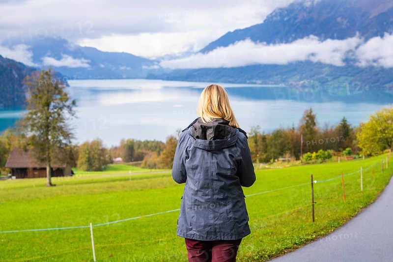 Woman looking at a calm lake, framed by mountains and clouds, Lake Brienz, Switzerland, Europe