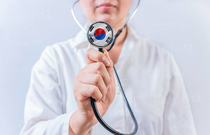 Female doctor holding stethoscope with South Korean flag. South Korean Health and Care concept