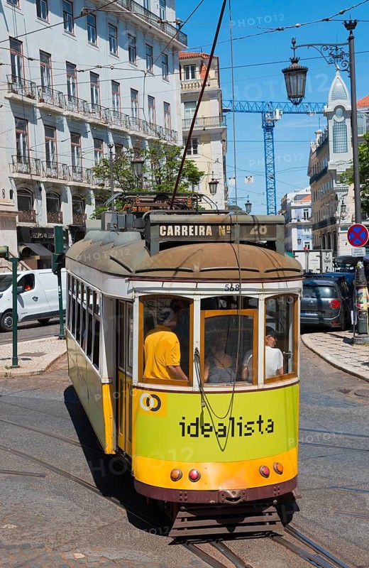 Yellow-green tram bends around a curve through the city, Tram, Line 28, Carros eléctricos de Lisboa, Eléctricos de Lisboa, Old Town, Lisbon, Portugal, Europe