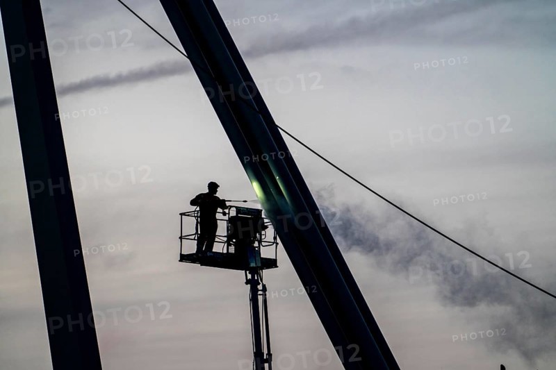 Worker cleans a bridge pier with a high-pressure cleaner on a cherry picker at the Erasmus Bridge over the Nieuwe Maas in Rotterdam, Netherlands