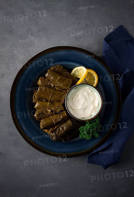 Dolma, cabbage rolls, grape leaves with filling, white sauce, lemon and herbs, rustic, selective focus, no people