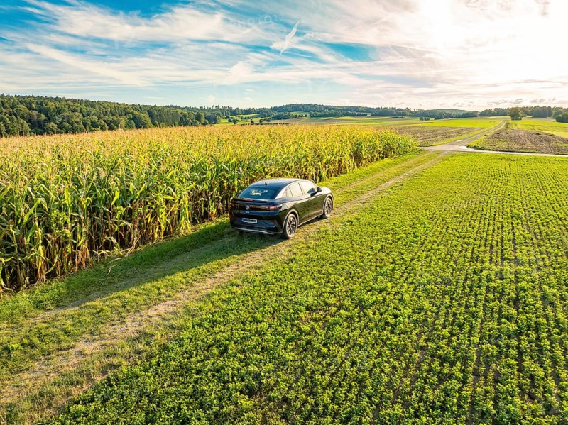 Black car driving on a dirt track along a high corn field under a blue, slightly cloudy sky, Carsharing, VW ID5, Calw, Black Forest, Germany, Europe