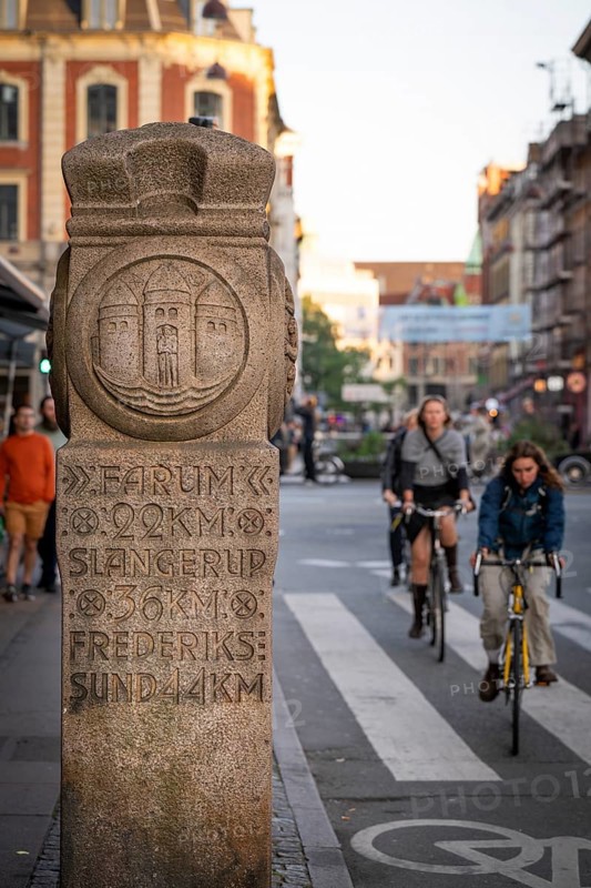 Historical stone with kilometre markers shows distances, cyclists, Nørreport, Copenhagen, Denmark, Europe