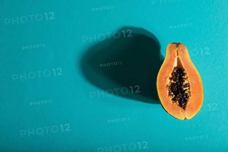Ripe cut papaya on blue pastel background. Top view, flat lay, copy space, hard light. Tropical, healthy food, women health concept, minimalism