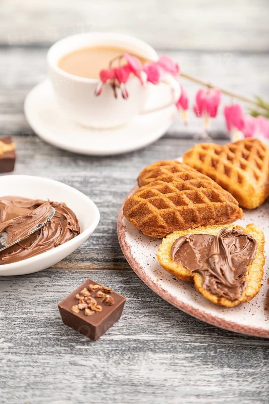 Homemade waffle with chocolate butter and cup of coffee on a gray wooden background. side view, selective focus, close up