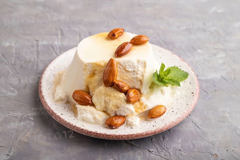 Ricotta cheese with honey and almonds on gray concrete background. side view, close up