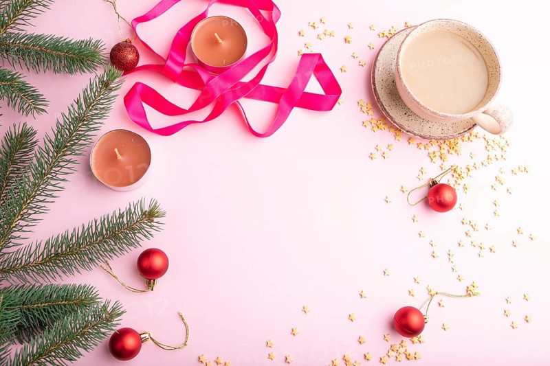 Christmas or New Year frame composition. Decorations, red balls, fir and spruce branches, cup of coffee, candles on a pink paper background. Top view, copy space, flat lay