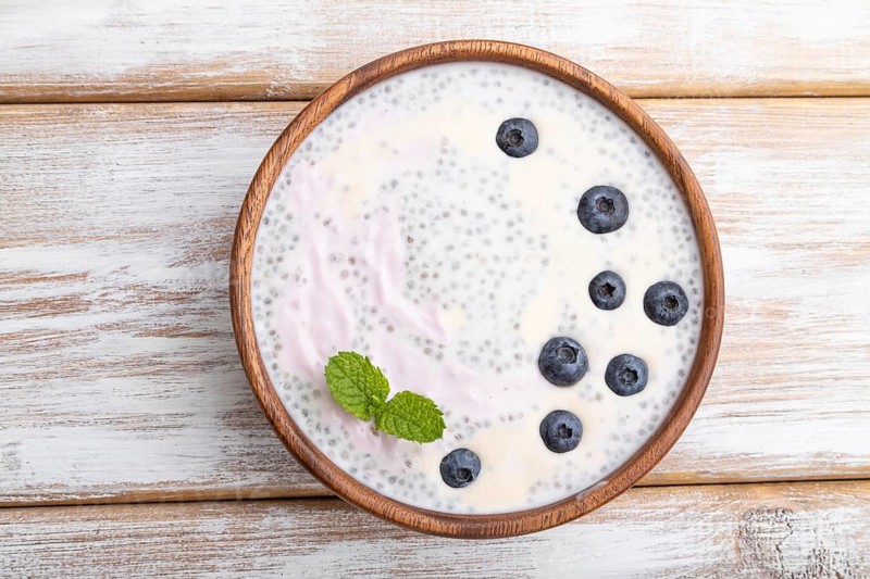 Yogurt with blueberry in wooden bowl on white wooden background. top view, flat lay, close up