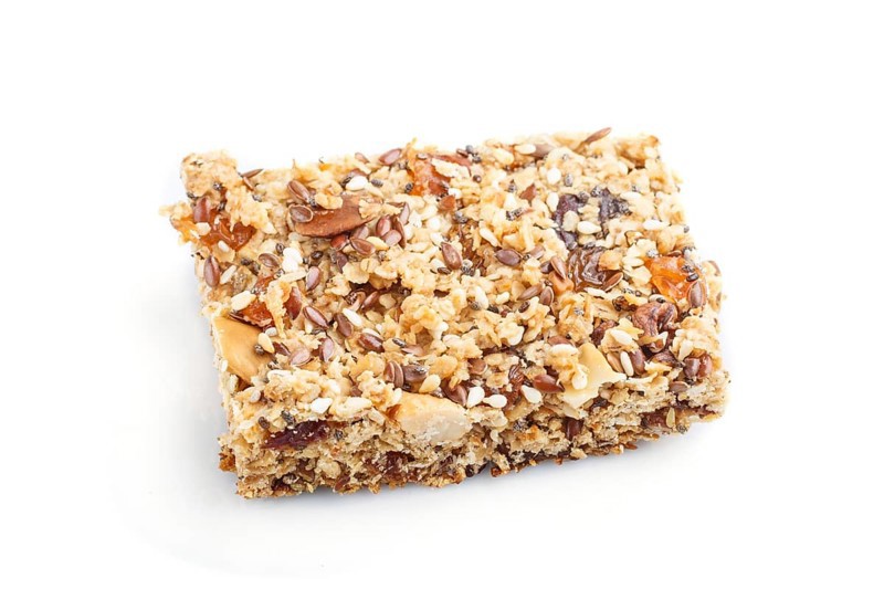 Homemade granola from oat flakes, dates, dried apricots, raisins, nuts isolated on white background. Side view, close up, macro