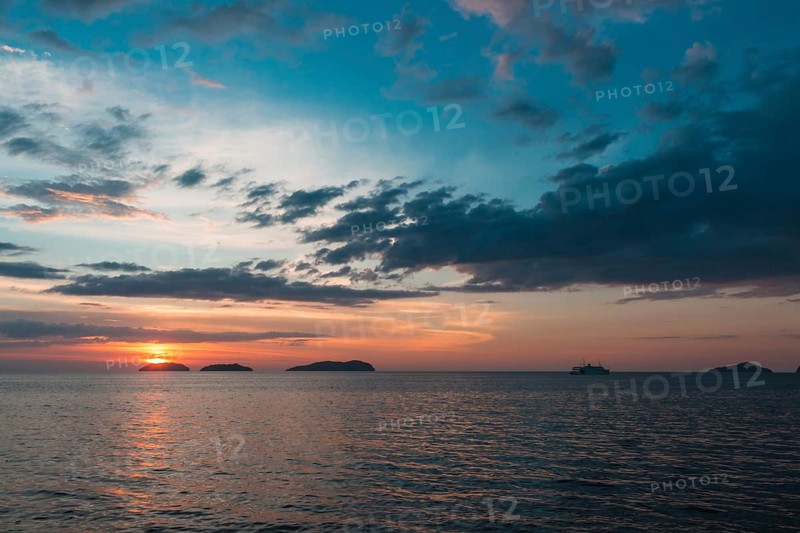 Beautiful purple sunset on the sea with small islands on the horizon