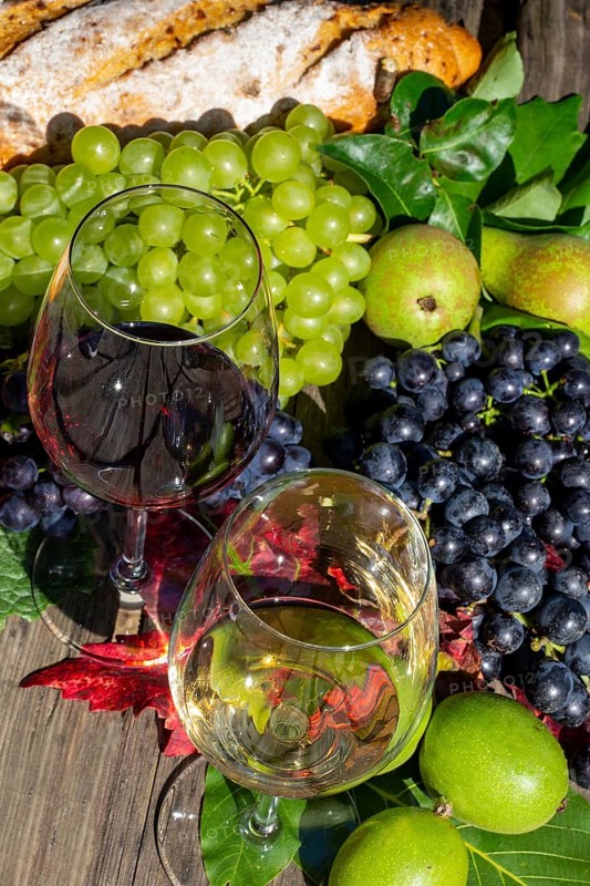 Symbolic image of grape grape harvest: Ripe grapes decorated with wine glasses on a wooden table
