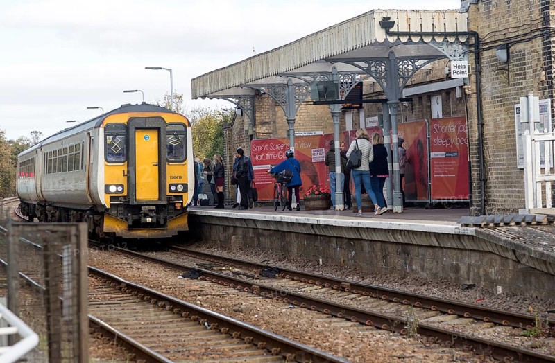 Passengers on platform train arriving, railway station, Saxmundham, Suffolk, England, UK British Rail Class 156 Super Sprinter diesel multiple unit Greater Anglia train