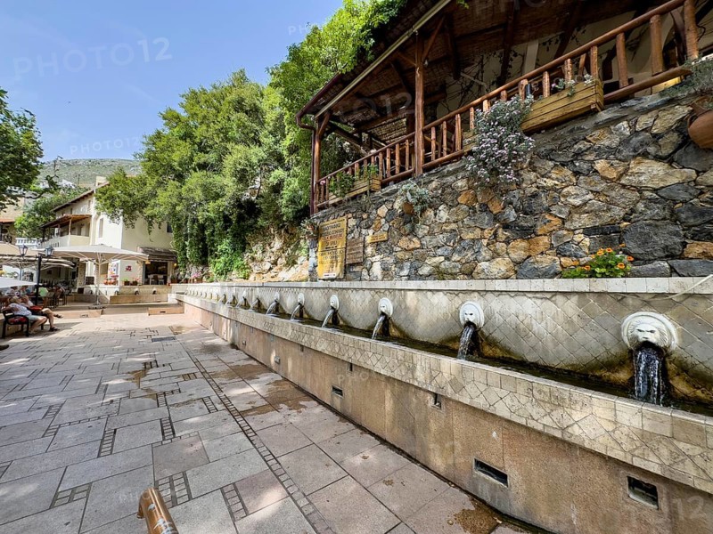 Lion fountain Venetian fountain Kefalovrisi with 25 water spouts in the shape of a lion's head lion's head underneath collecting basin on the main square of Spili village with drinking water, Spili, Crete, Greece, Europe