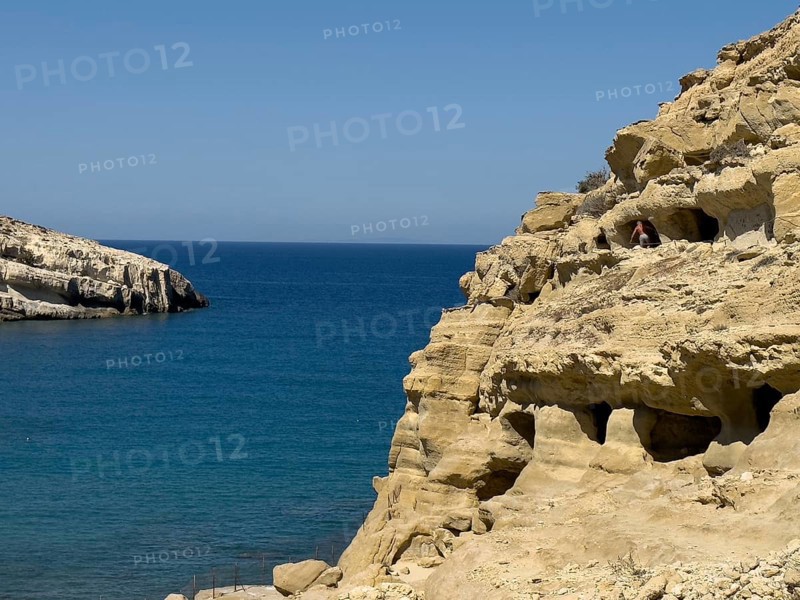 View of entrances of caves in sandstone rocks of former Roman necropolis with sandstone caves carved into sandstone Cave tombs Grottoes in rocks on the north side of Matala Bay, in the 60s and 70s hippie caves Caves for dropouts and hippies today excursion destination on the south coast of Crete island, left at the edge of the picture Libyan Sea Mediterranean, Matala, Crete, Greece, Europe