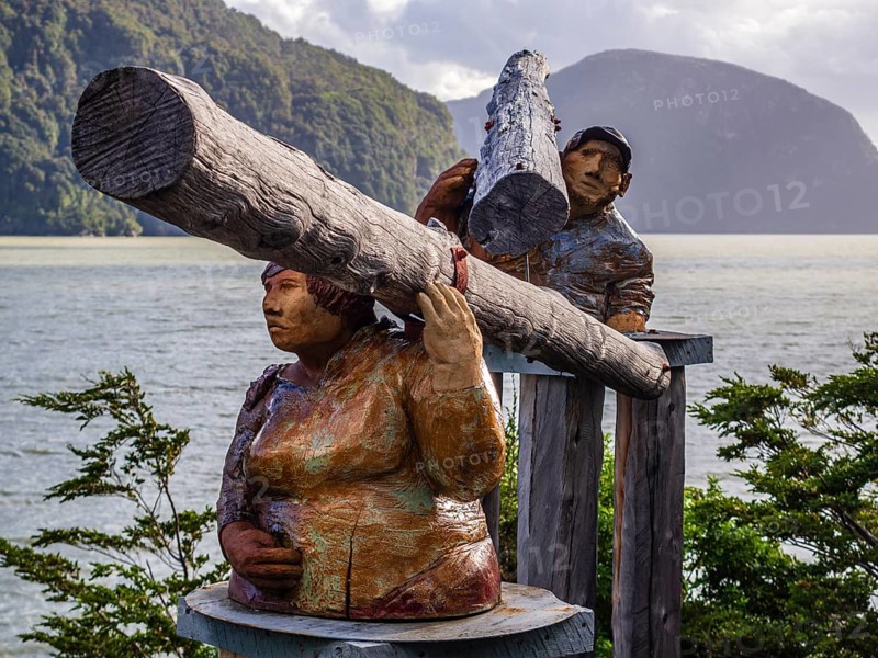 Sculputure of man and woman carrying trunks of a tree, seaside of Caleta Tortel, Caleta Tortel, Aysen region, Patagonia, Chile, South America