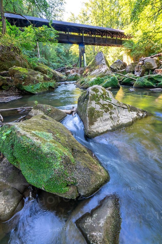 The Irrel Waterfalls, rapids in the lower reaches of the Prüm, covered wooden bridge for hikers, between Prümzurlay and Irrel, in the Eifel district of Bitburg-Prüm, Rhineland-Palatinate. Germany