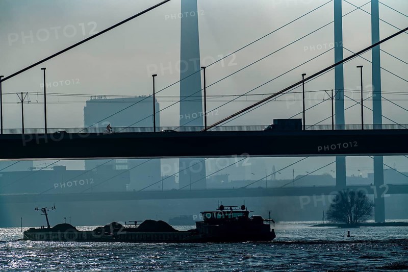 Dense fog slowly lifting, cargo ships on the Rhine near Düsseldorf, in front the Oberkassler bridge, behind it the Rheinknie bridge, North Rhine-Westphalia, Germany, Europe