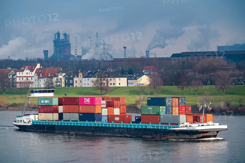 The river Rhine near Duisburg, houses on the Rhine dyke, Laar district, Thyssenkrupp Steel steelworks in Bruckhausen, cargo ship, Duisburg, North Rhine-Westphalia, Germany, Europe