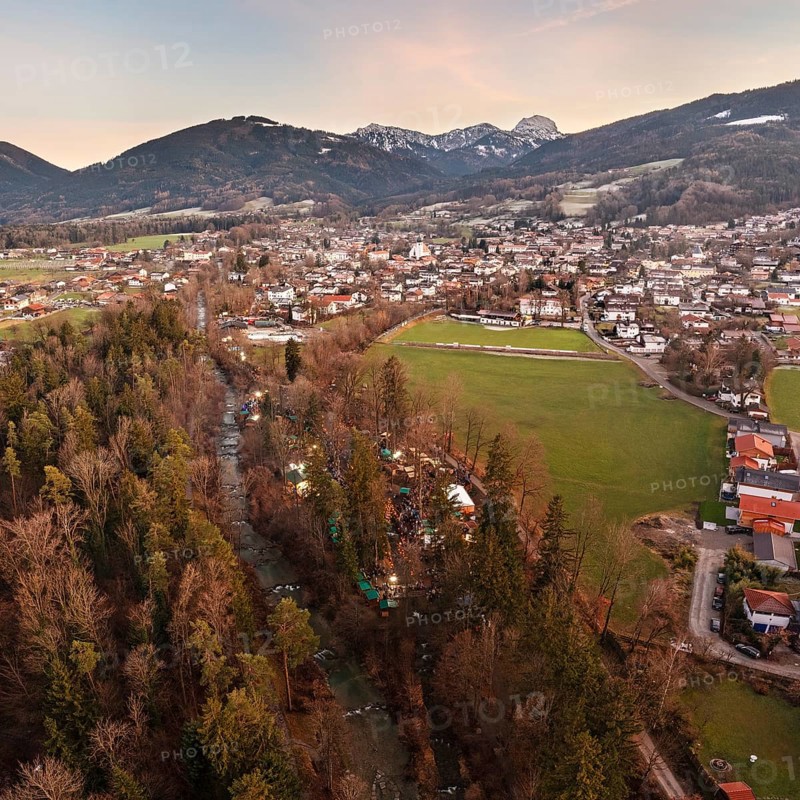 View of a village with a river and snow-capped mountains in the background, surrounded by green meadows, Waldadvent event, Bad Feilnbach