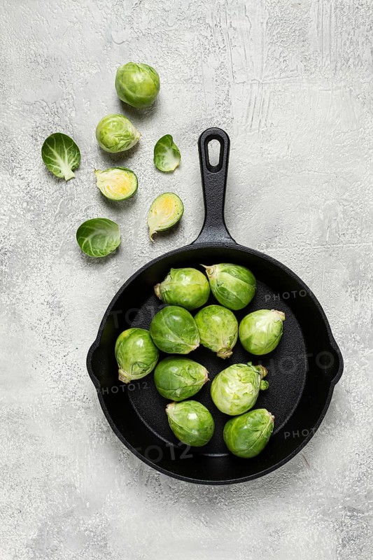 Fresh Brussels sprouts, raw, in a cast-iron pan, top view, on a gray table, no people