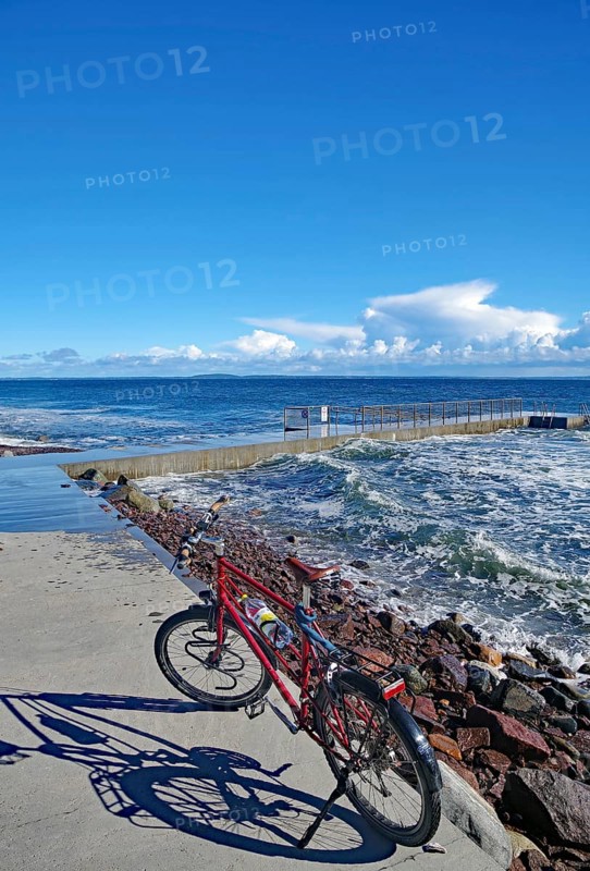 Sun shining on a bicycle on a coastal promenade with a view of the sea and waves, Tönsberg, Oslofjord, Norway, Europe