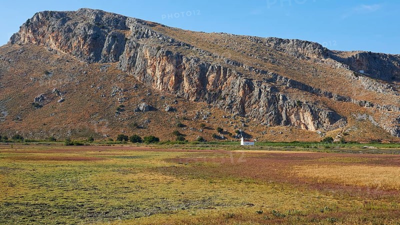A small white chapel at the foot of a mountain surrounded by meadows, Strofilia biotope, wetlands, Kalogria, Peloponnese, Greece, Europe