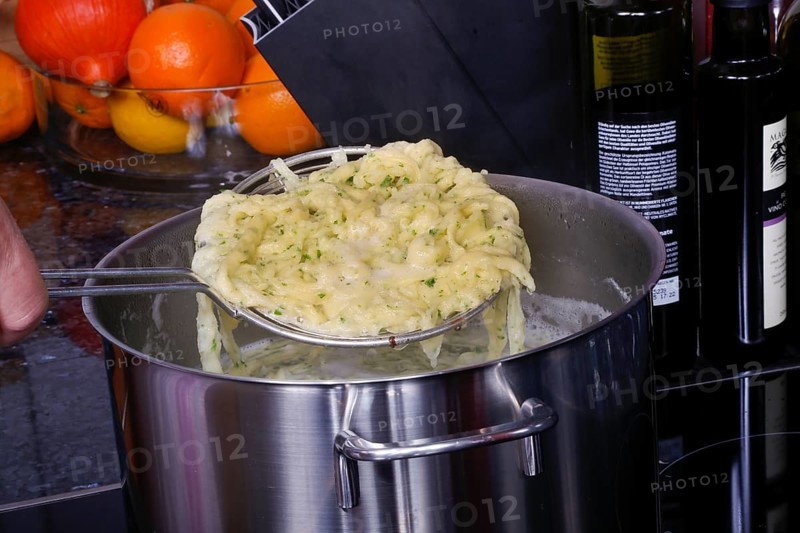 Swabian cuisine, preparation of herb spaetzle for roast beef, scooping spaetzle from boiling water, cooking pot, slotted spoon, spaetzle scoop, savoury, salty, typical Swabian, home cooking, traditional cuisine, food photography, studio, Germany, Europe